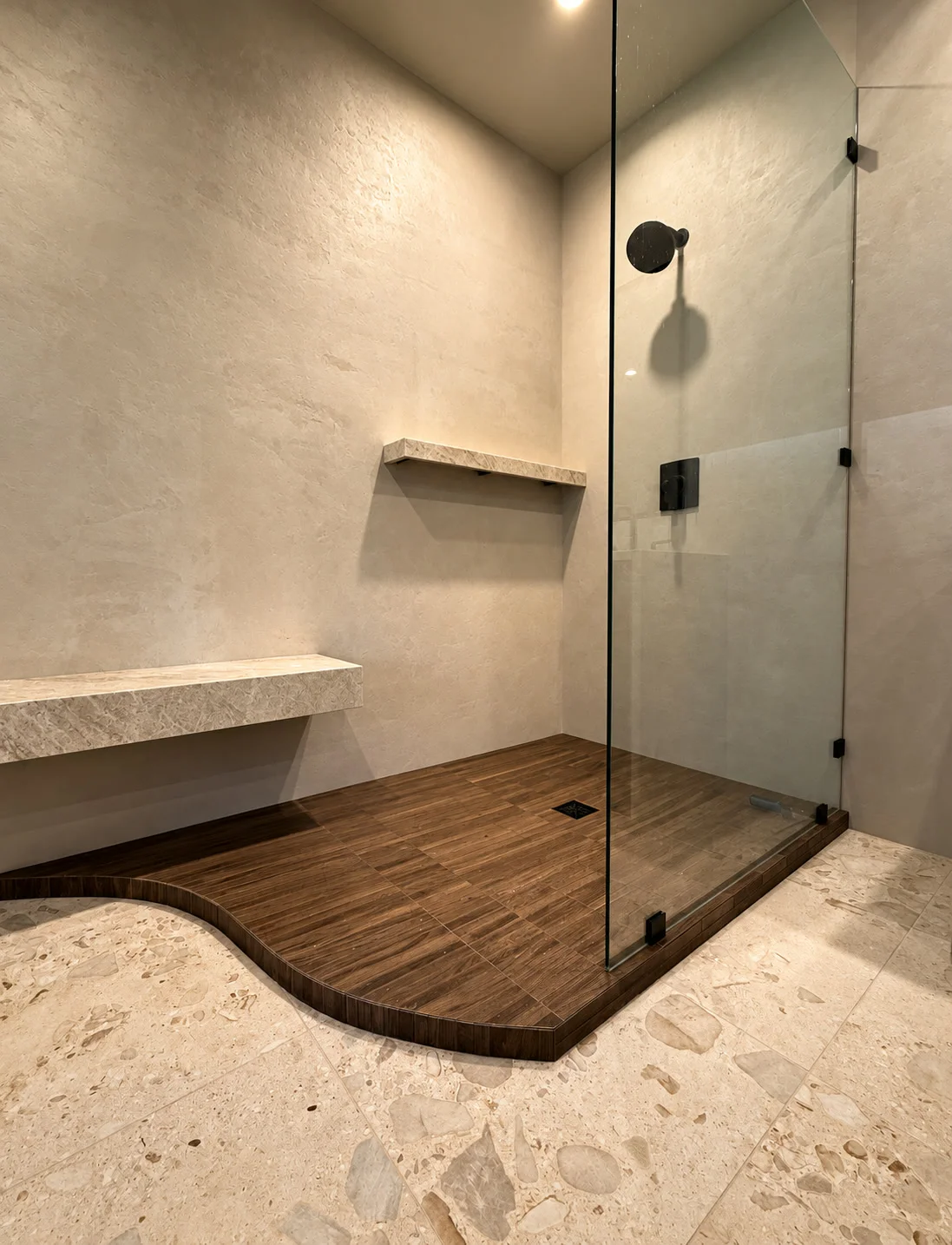 Custom curved walk-in shower with wood-grain tile floor and glass enclosure