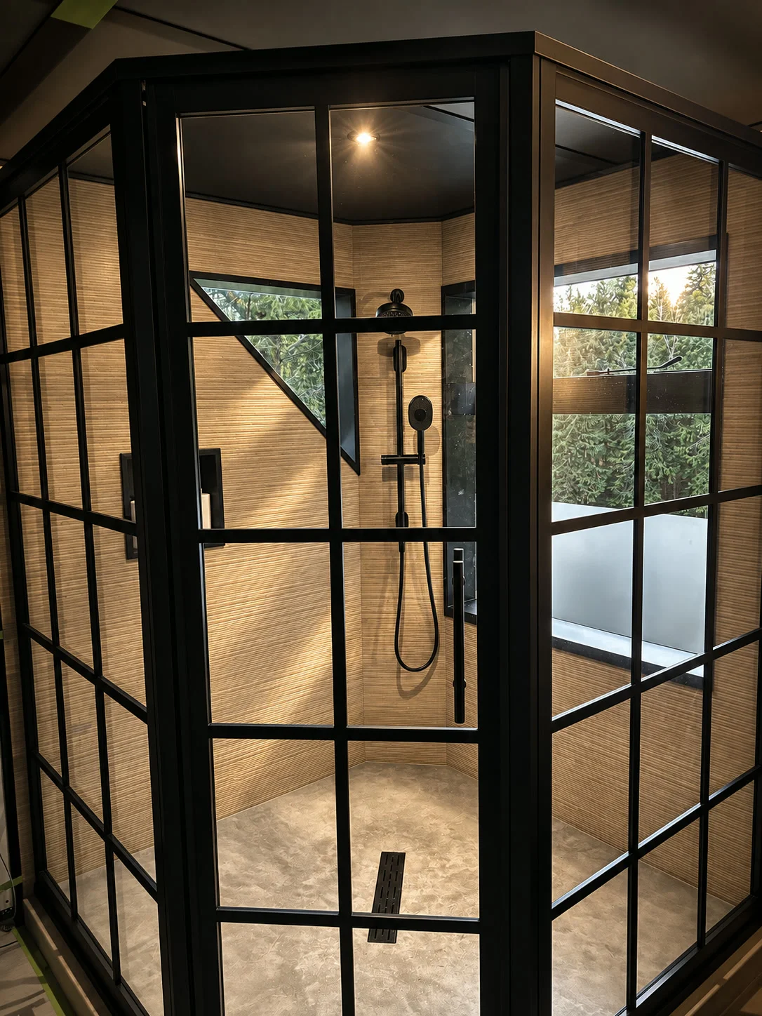 Walk-in shower enclosure with black steel grid frame and stone floor